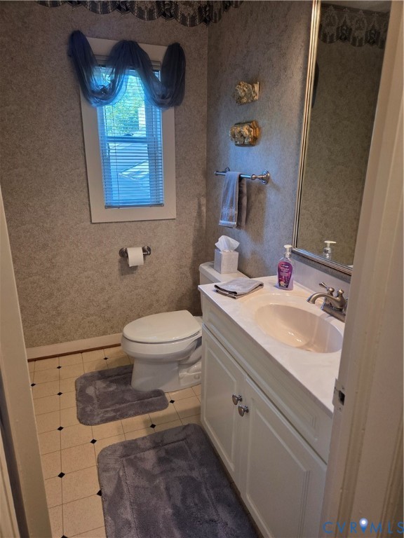 7733 Rock Creek Road Henrico, VA 23229 - Photo 46 of 73 a bathroom with a granite countertop toilet a sink and a mirror