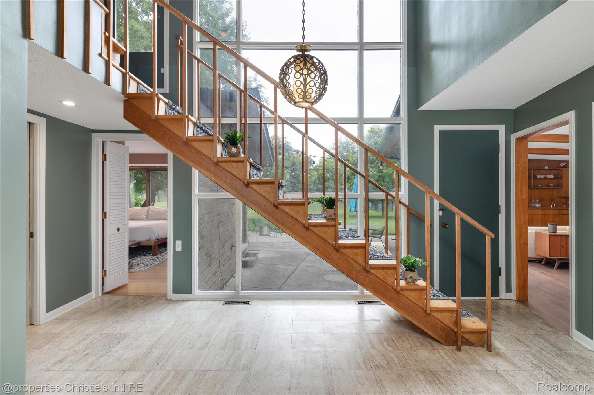 2771 West Seven Mile Road Detroit, MI 48221 - Photo 2 of 57 Wood-finish staircase with open risers and minimalist railing, set against a two-story window wall