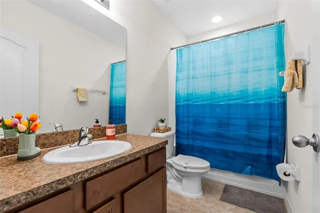 a bathroom with a granite countertop sink a toilet a mirror and shower