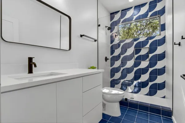 a bathroom with a sink a toilet a mirror and shower