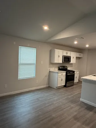 a kitchen with stainless steel appliances a white cabinets and a wooden floor