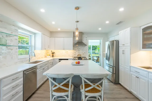 a kitchen with stainless steel appliances granite countertop a stove a refrigerator a sink dishwasher a dining table and chairs with wooden floor