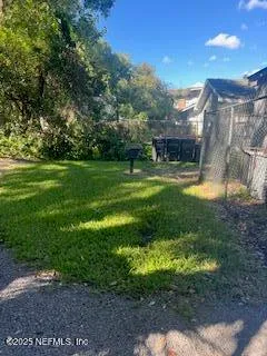 a view of a big yard with plants and large trees