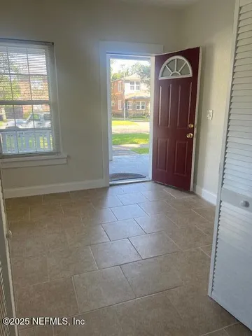 a view of hallway with a door and chandelier