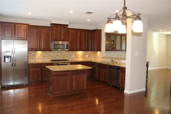 a kitchen with kitchen island granite countertop wooden floors white cabinets and stainless steel appliances