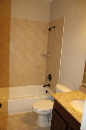 a bathroom with a granite countertop bathtub sink vanity mirror and toilet