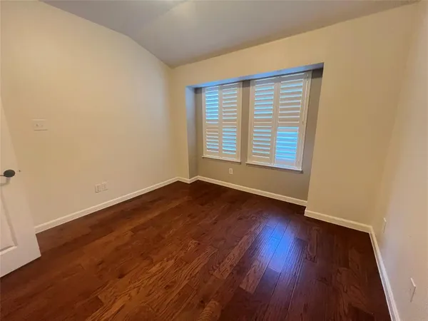 an empty room with wooden floor and entrance