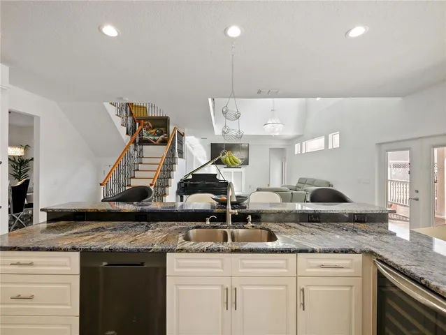 a kitchen with granite countertop white cabinets and stainless steel appliances