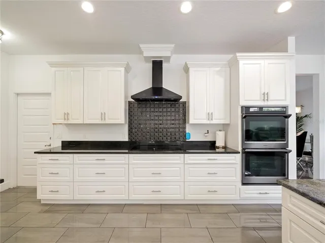 a kitchen with granite countertop white cabinets stainless steel appliances and a counter space