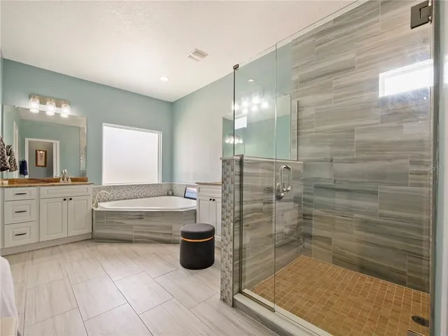 a spacious bathroom with a granite countertop sink a mirror and a bathtub