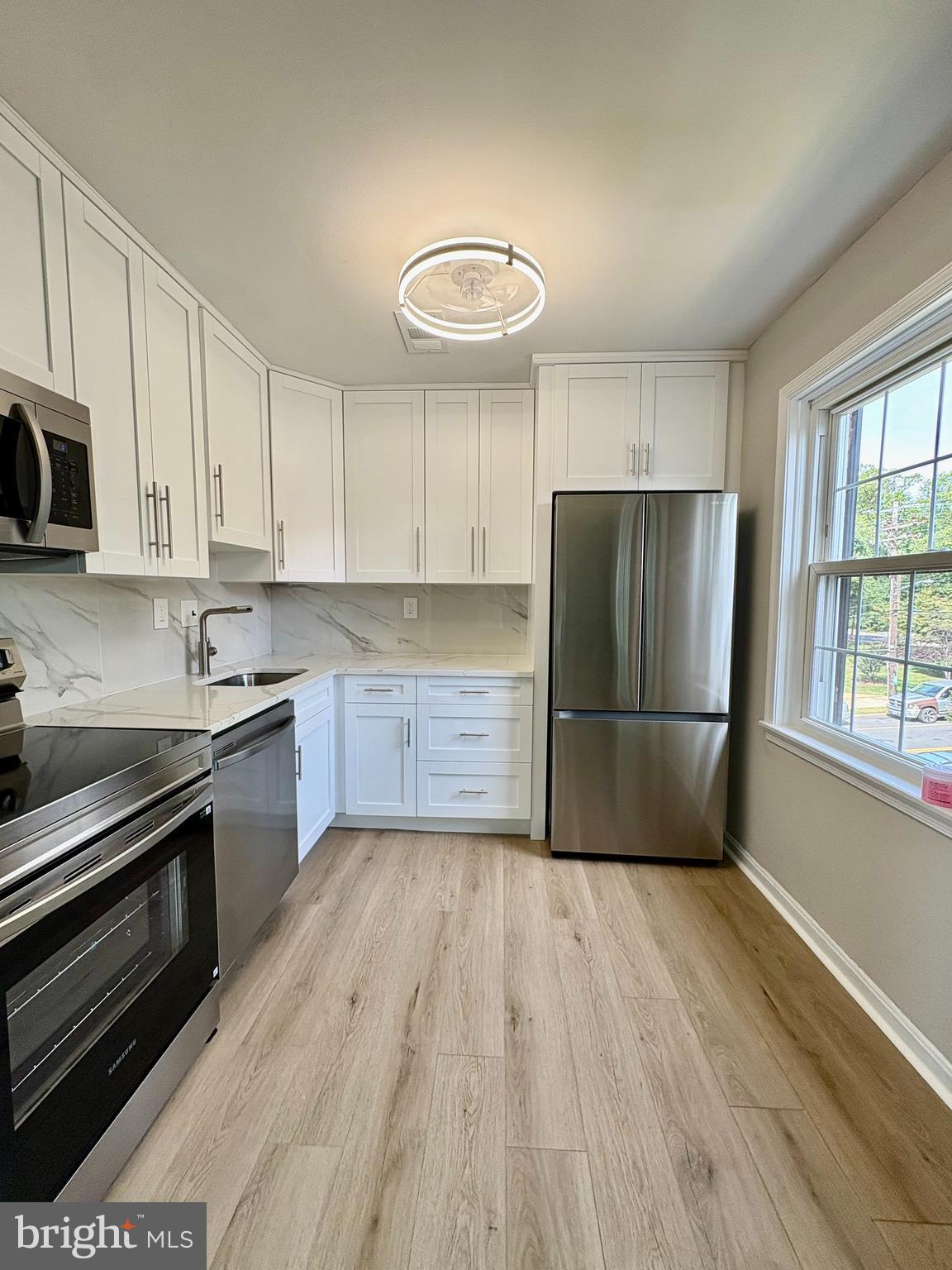 2008 38th Street Southeast, Unit 302 Washington, DC 20020 - Photo 8 of 25 a kitchen with wooden floors stainless steel appliances and window