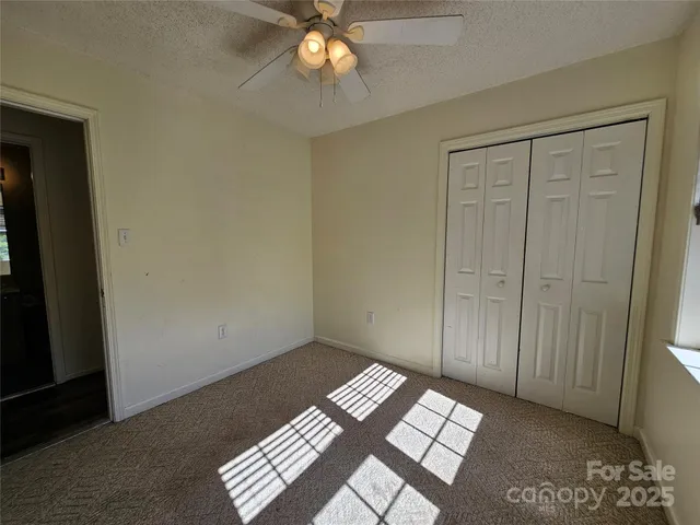an empty room with wooden floor closet and windows