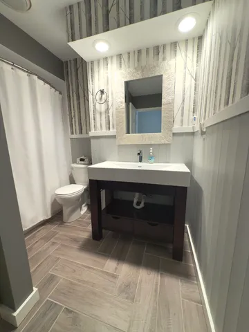 a bathroom with a sink toilet a mirror and shower