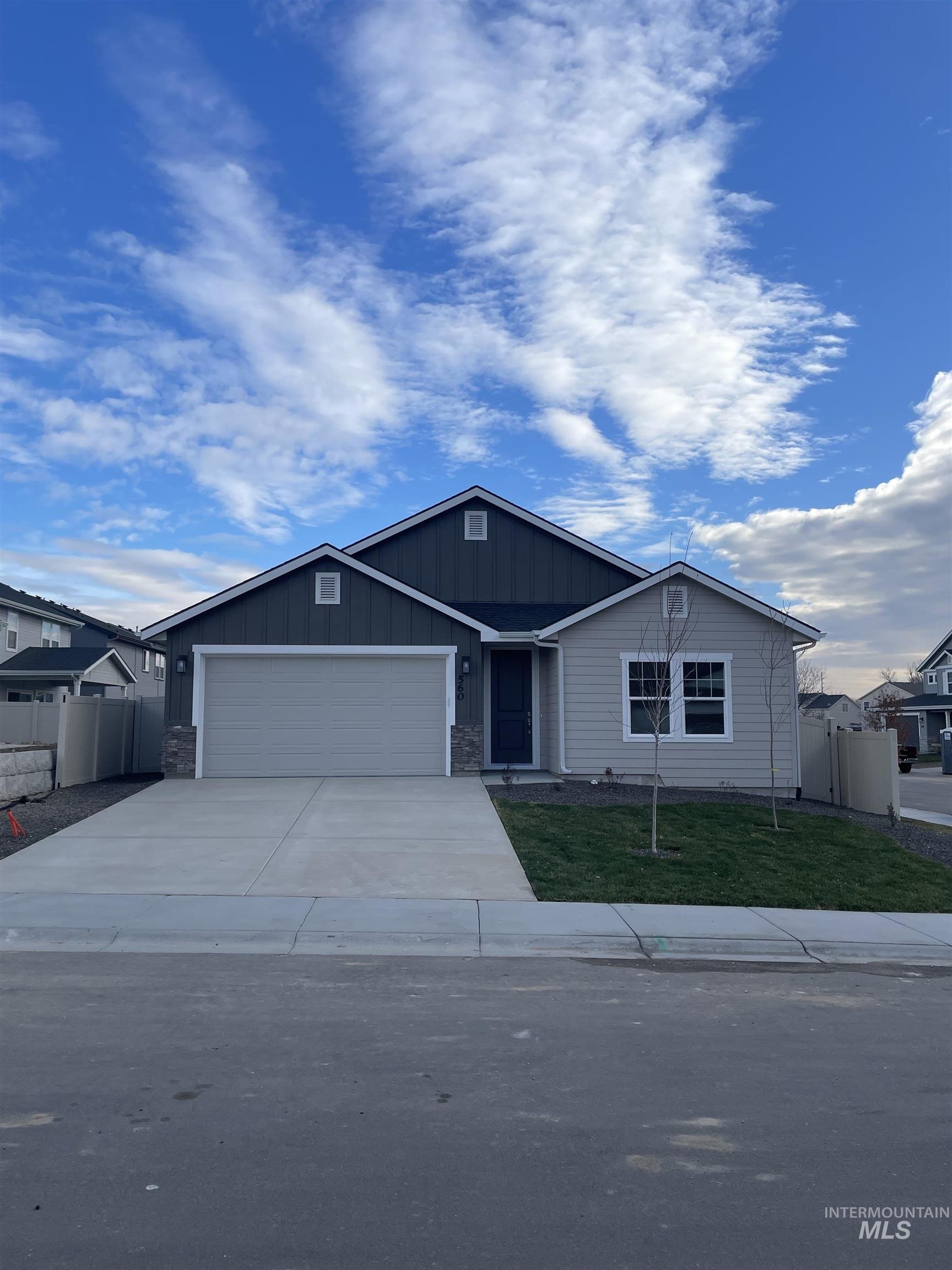 Ranch-style home with a garage, driveway, board and batten siding, and stone siding