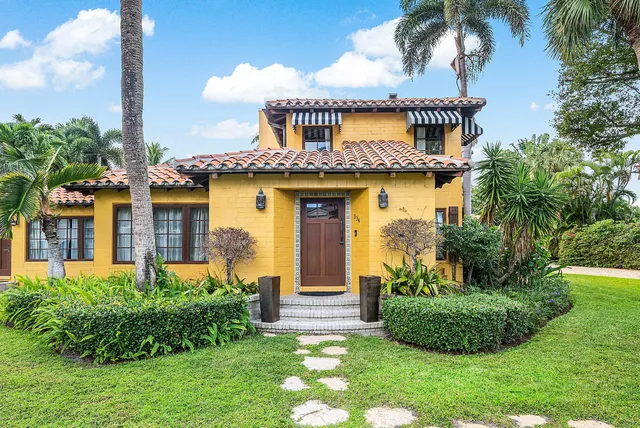 a view of a house with a yard and potted plants