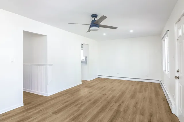 an empty room with wooden floor and ceiling fan