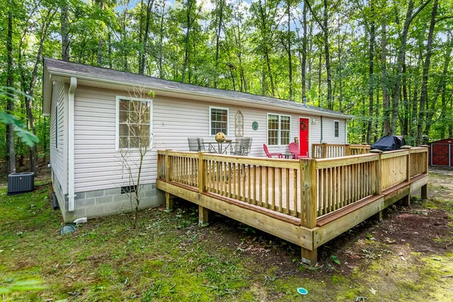 a view of a house with a yard and deck area under a large tree