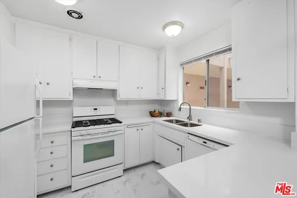 a kitchen with cabinets appliances a sink and a counter top