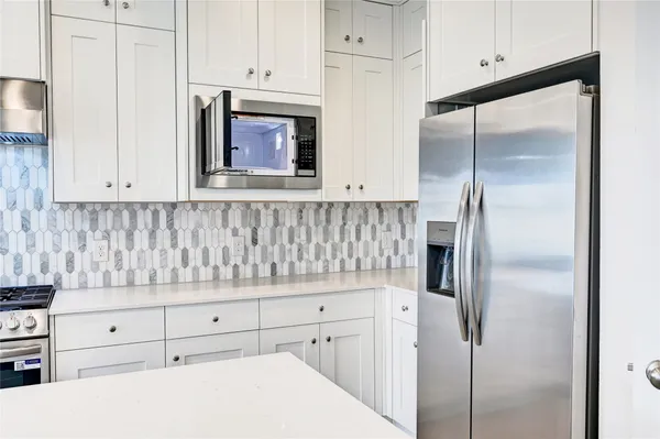 a kitchen with white cabinets and refrigerator