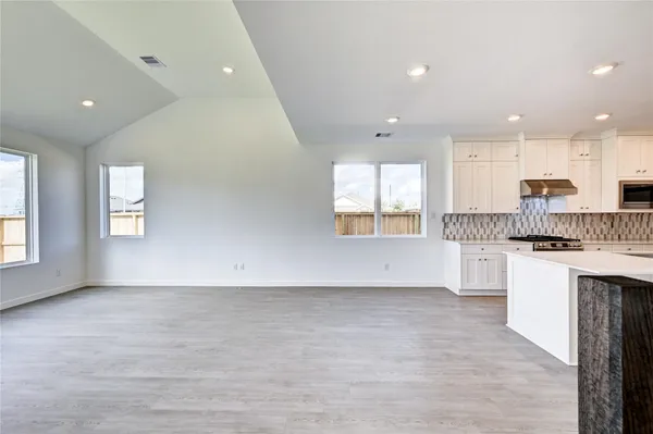 a open kitchen with white cabinets and wooden floor