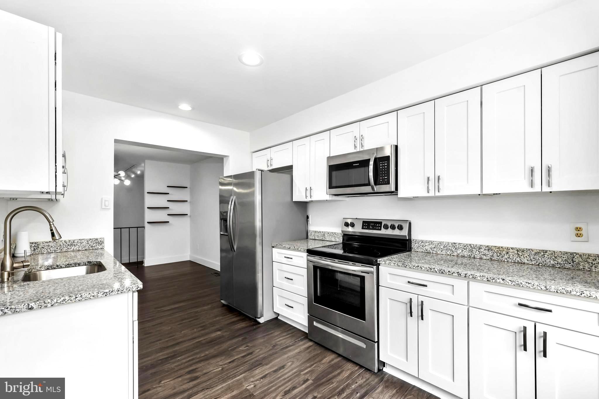 11711 Decade Court Reston, VA 20191 - Photo 2 of 44 a kitchen with stainless steel appliances granite countertop a stove top oven a refrigerator a sink and dishwasher with wooden floor