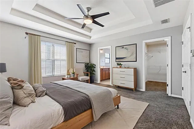 a spacious bedroom with a bed a couch and a ceiling fan