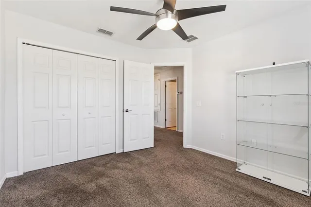 an empty room with closet and a ceiling fan