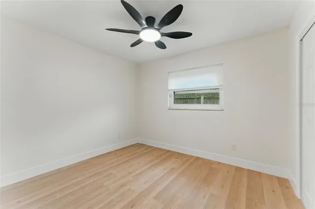 an empty room with a window and a fan