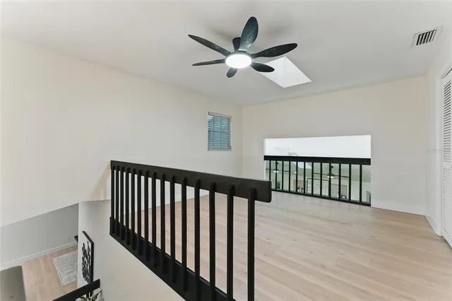 a view of a room with wooden floor and a ceiling fan