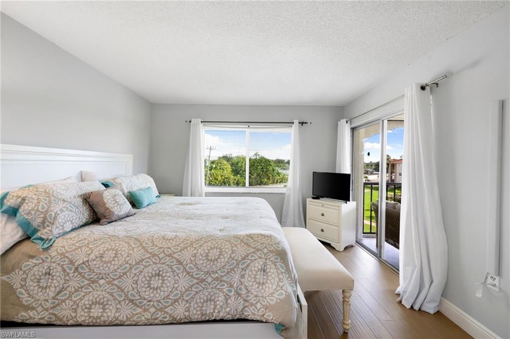 5 High Point Circle West, Unit 307 Naples, FL 34103 - Photo 16 of 31 Bedroom with a textured ceiling, access to exterior, and wood finished floors