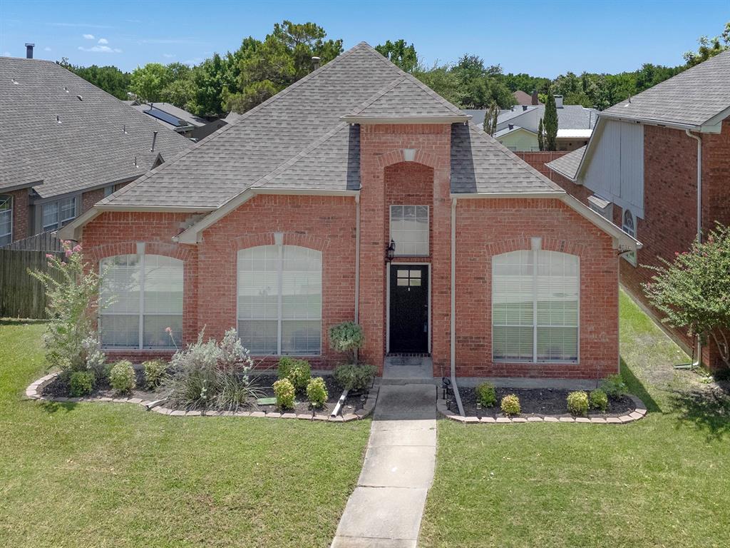 4234 Timberglen Road Dallas, TX 75287 - Photo 1 of 32 Brick exterior home featuring a gabled roofline, arched windows, and a manicured front lawn with established landscaping