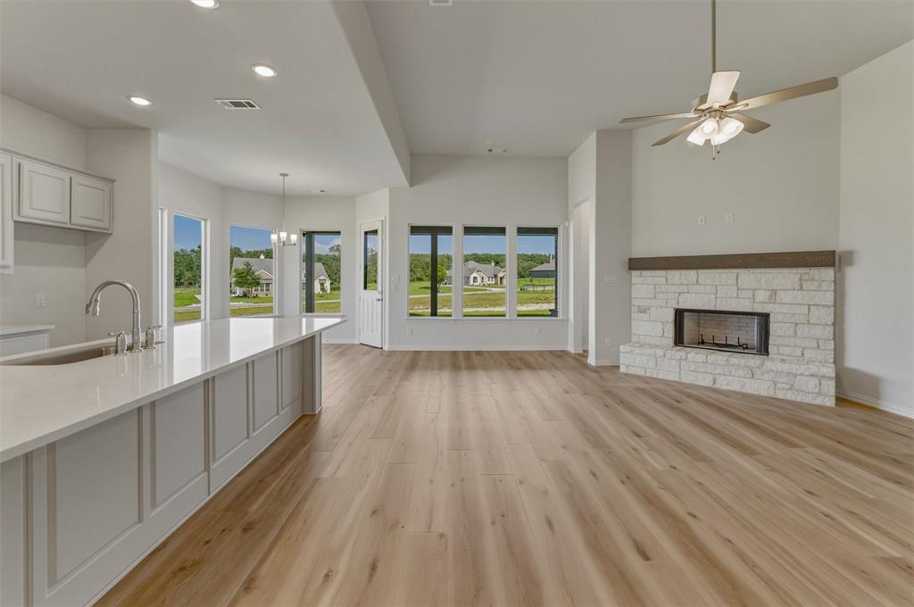 605 Tay Tay Way Springtown, TX 76082 - Photo 6 of 31 Spacious open-concept living area featuring wood-finish flooring, a stone fireplace with a wood mantle, and a ceiling fan