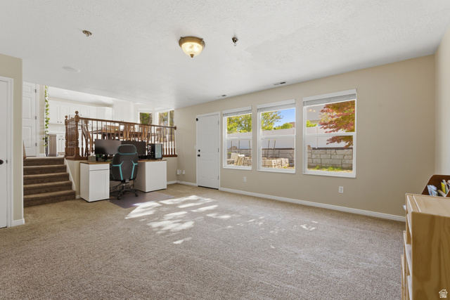 11189 Ohenry Road East Sandy, UT 84070 - Photo 24 of 44 Carpeted living area featuring three large windows, a white door, and a built-in wood railing system with stairs