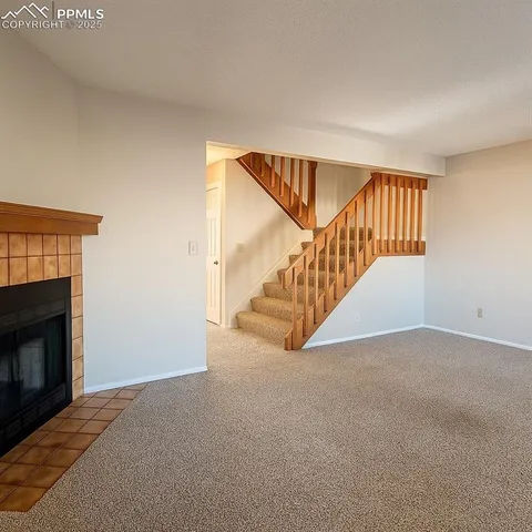 a view of an empty room with stairs and a fireplace