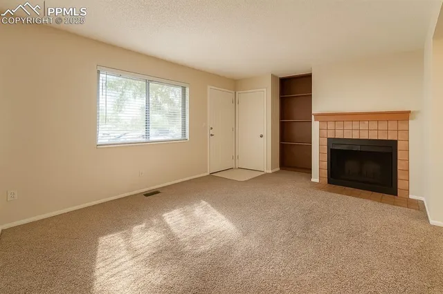 a view of an empty room with a window and fireplace