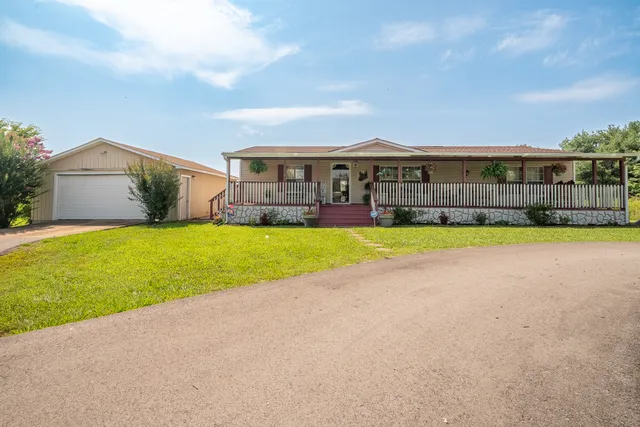 a view of a house with a big yard and large trees
