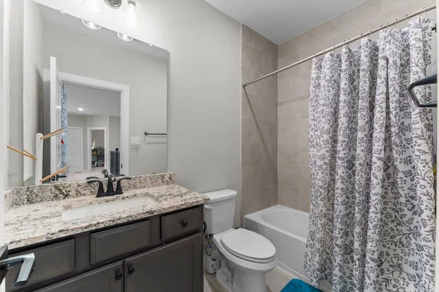 a bathroom with a granite countertop sink a toilet and shower