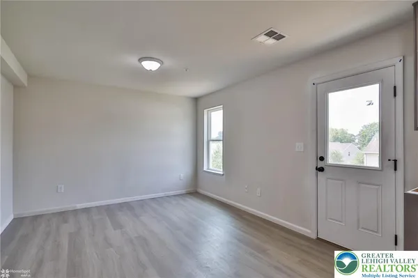 a view of an empty room with wooden floor and a window