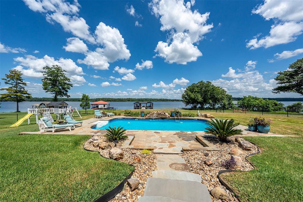 16241 Big Oak Bay Road Tyler, TX 75707 - Photo 31 of 40 Lakeside property featuring an in-ground swimming pool with stone surround, a stone pathway, and a grassy lawn