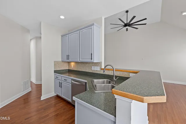 a kitchen with stainless steel appliances granite countertop a sink a stove and a wooden floors