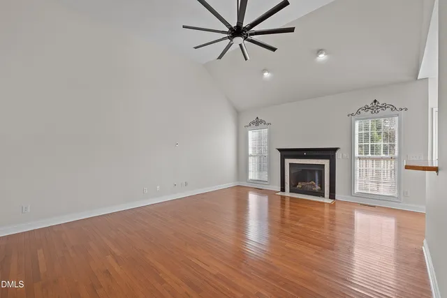 an empty room with windows fireplace and a sink