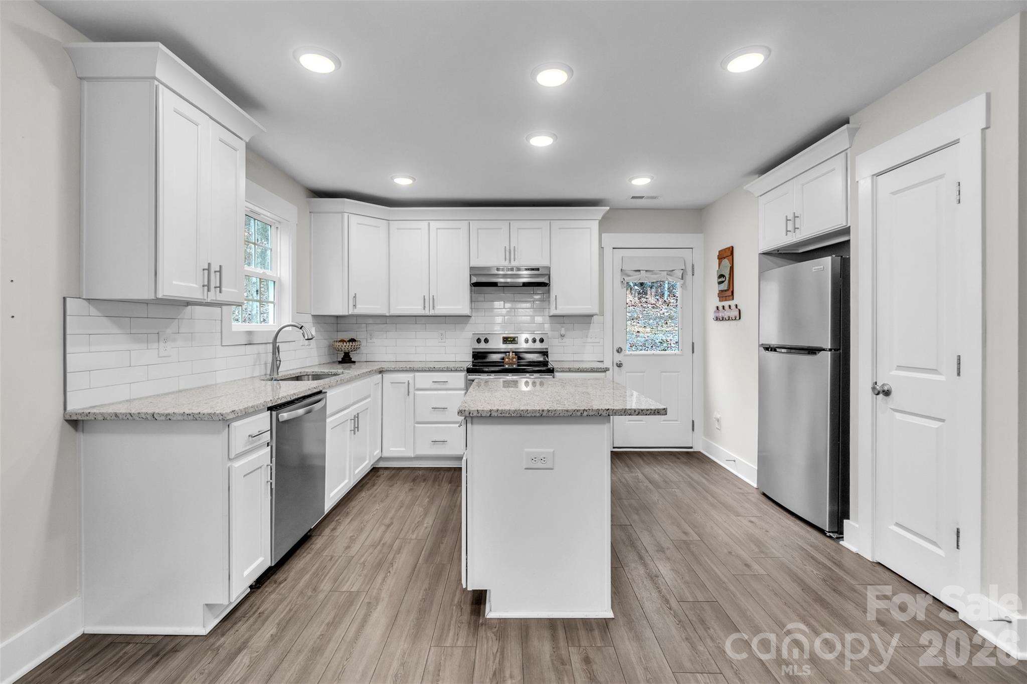 518 Lake Head Road Norwood, NC 28128 - Photo 21 of 39 a kitchen with stainless steel appliances granite countertop a refrigerator a sink dishwasher a stove and white cabinets with wooden floor