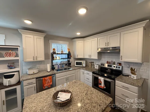 a kitchen with granite countertop a sink a stove a oven a counter space and cabinets