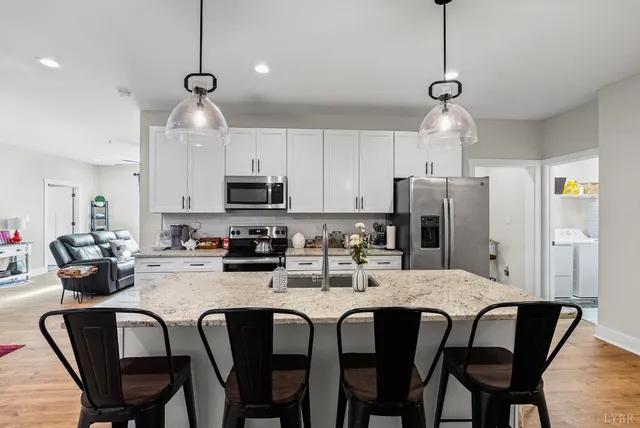 a kitchen with stainless steel appliances a dining table chairs refrigerator and microwave