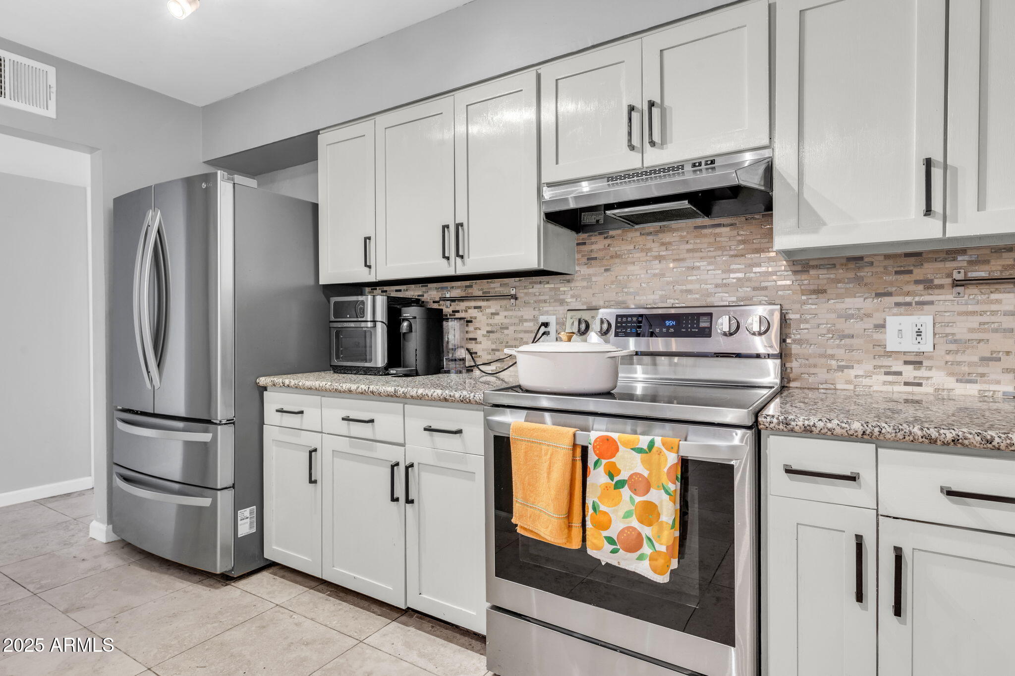 4928 East Palm Lane Phoenix, AZ 85008 - Photo 6 of 17 a kitchen with stainless steel appliances granite countertop a refrigerator a stove and white cabinets