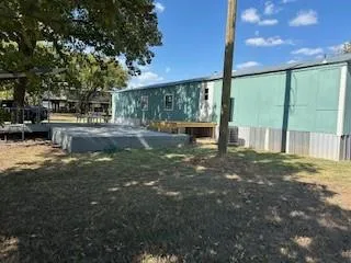 a backyard of a house with table and chairs under a large tree
