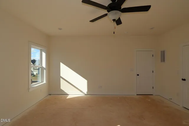 an empty room with windows and fan