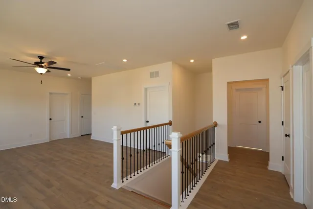 a kitchen with stainless steel appliances kitchen island granite countertop a refrigerator a sink a stove and white cabinets with wooden floor