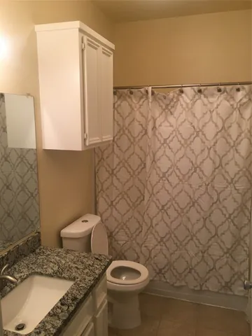 a bathroom with a granite countertop toilet and a sink