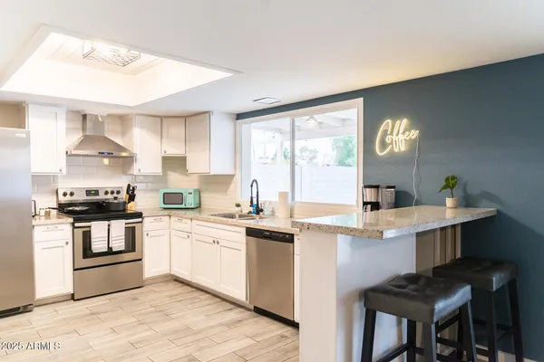 a kitchen with white cabinets appliances and a window